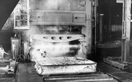A worker measures the width of a plate being rolled. Once the required width is acheived the plate will be rotated and rolled to length. — Hagley Museum & Library